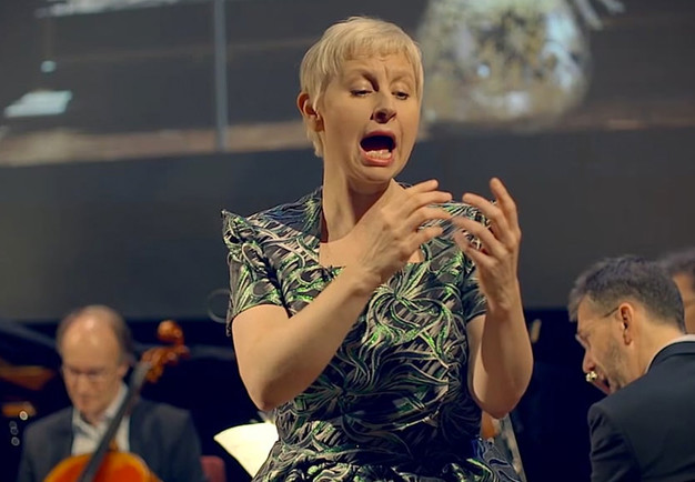 Utdrag ur filmen på en sjungande kvinna på scenen. Fotografi.