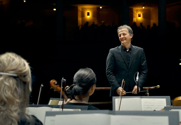 Man på podiet med ett leende. Utdrag ur filmen.