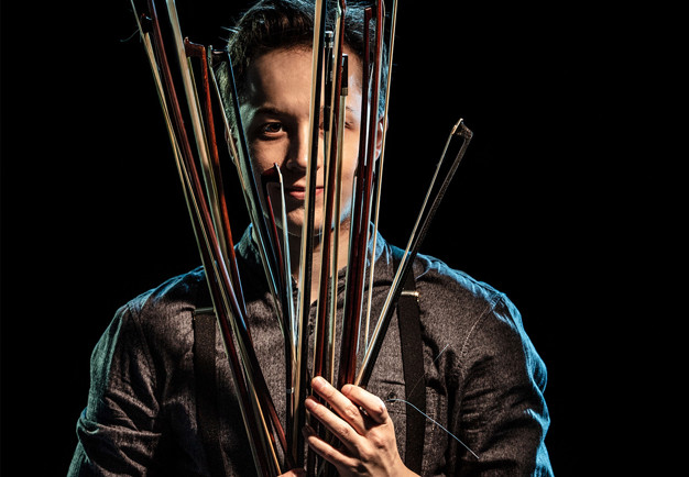 Man som håller i stråkar. Fotografi.