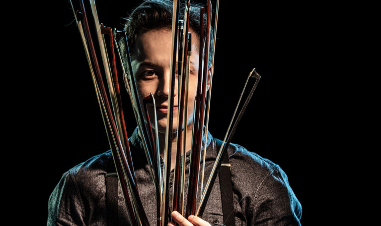 Man som håller i stråkar. Fotografi.