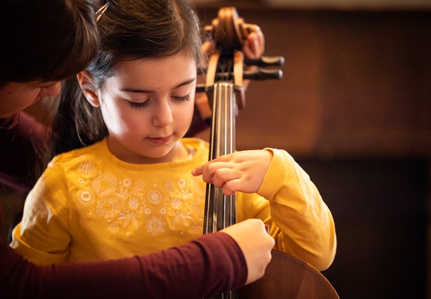 Flicka som provar cello. Fotografi.