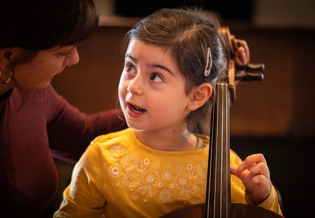 Liten tjej som spelar cello. Fotografi.