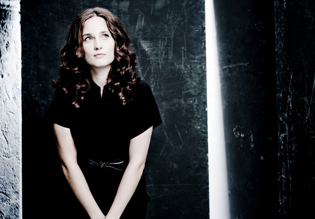 Kvinna som går framför en gul vägg. Fotografi.