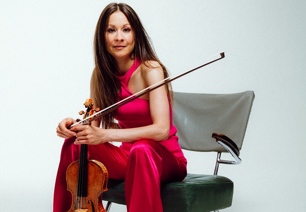 Kvinna med röd byxdress som sitter på en stol. Fotografi.