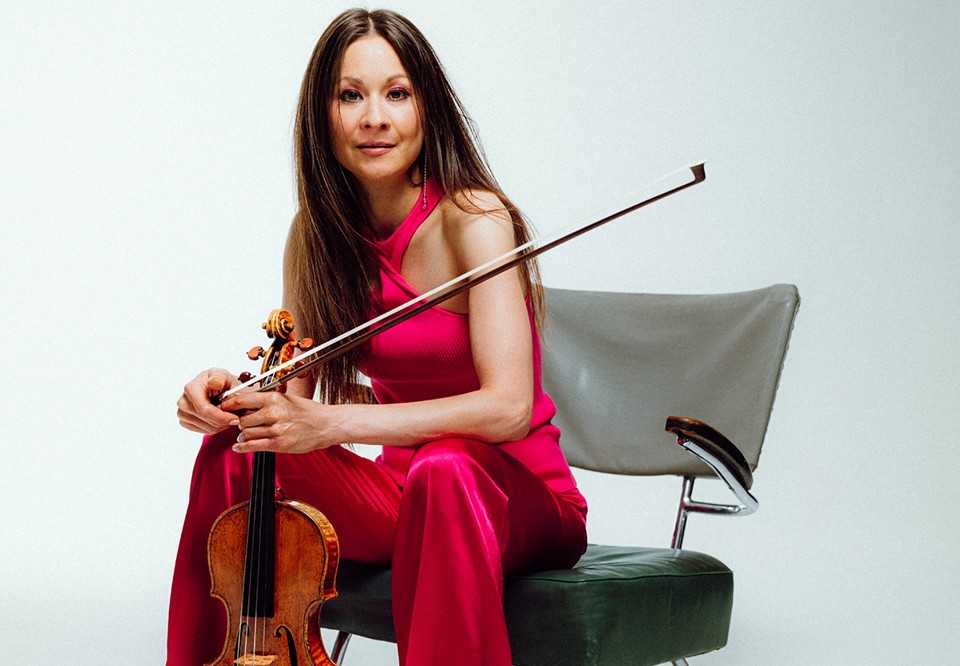 Kvinna med röd byxdress som sitter på en stol. Fotografi.