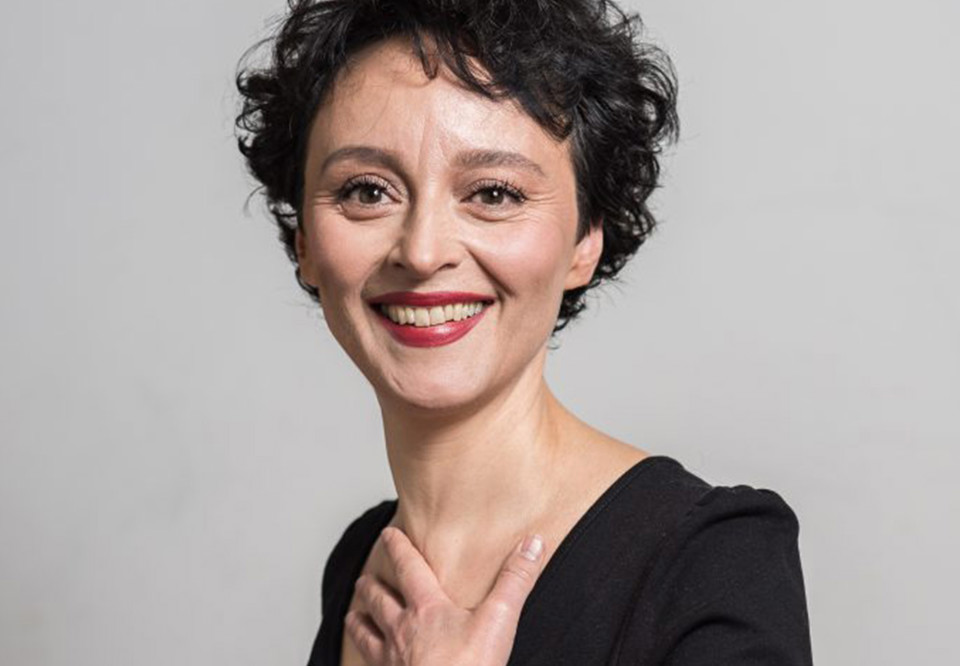 Kvinna med mörkt hår som ler. Fotografi.