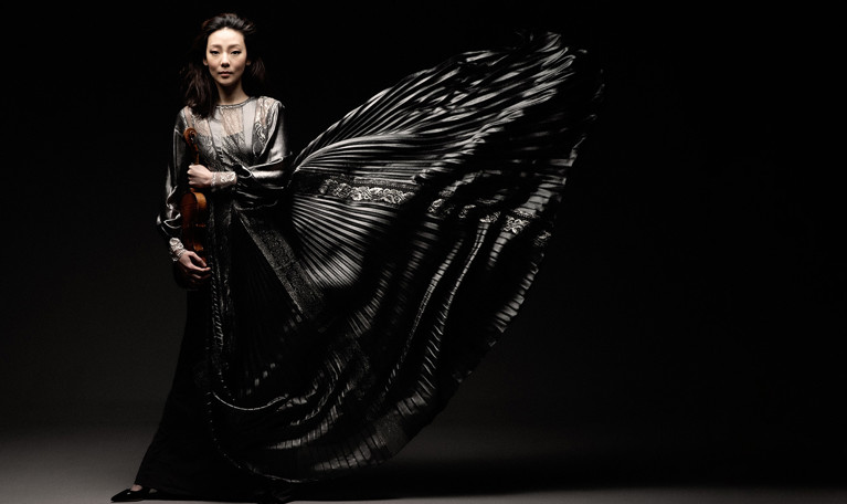 Kvinna som håller i en violin. Fotografi.