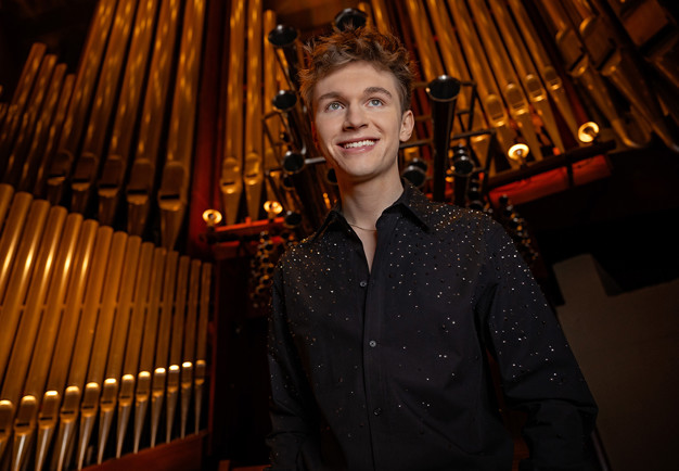 Ung kille framför orgel. Fotografi.