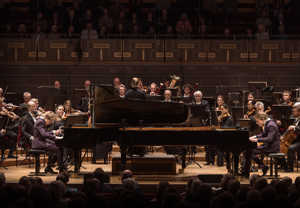 Två personer som spelar piano. Fotografi