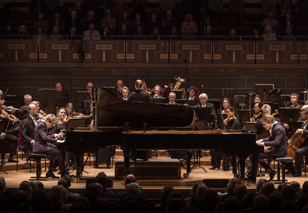 Två personer som spelar piano. Fotografi
