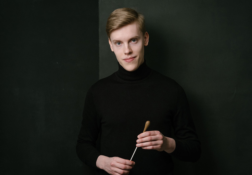 Man som håller i en dirigentpinne. Fotografi.