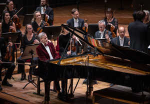 Man som lutar sig på ett piano. Fotografi.