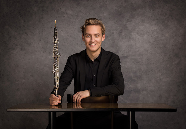 Porträttbild på en leende kvinna med flöjt framför sig. Fotografi.