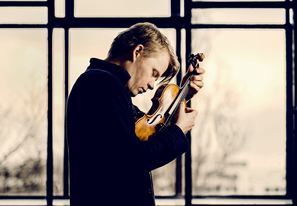 Man som står mot en grön vägg. Fotografi.