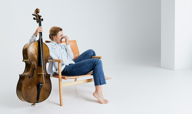 Kvinna som sitter på en stol med en cello. Fotografi