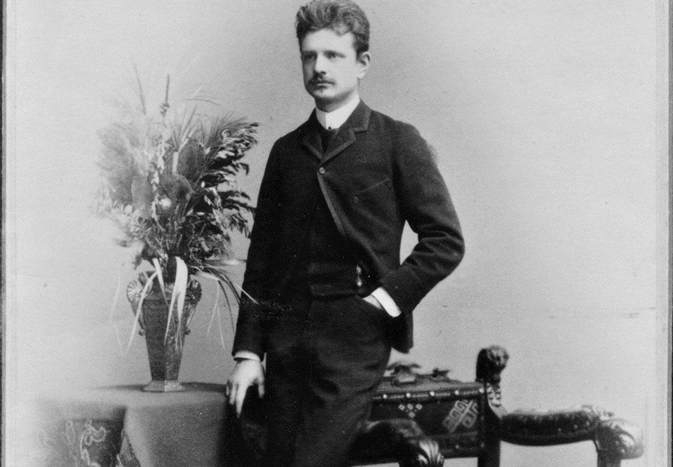 Man med kostym med ena handen i fickan. Fotografi.